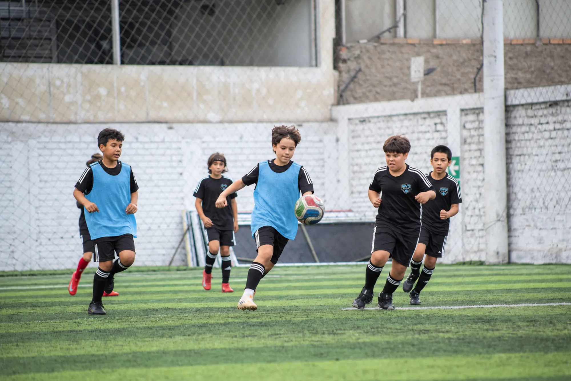 Kids in sky-blue training bibs playing a possession game during practice