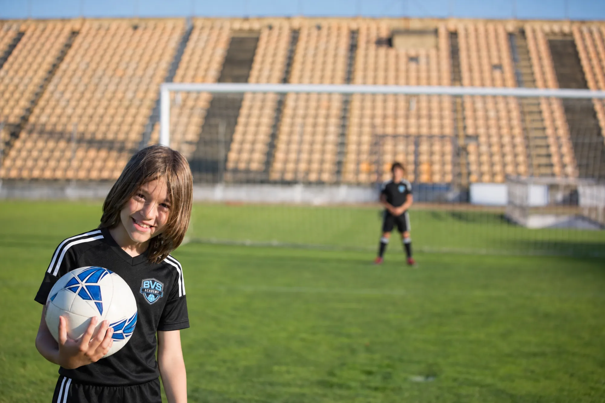 Smiling girl holding a soccer ball on the field