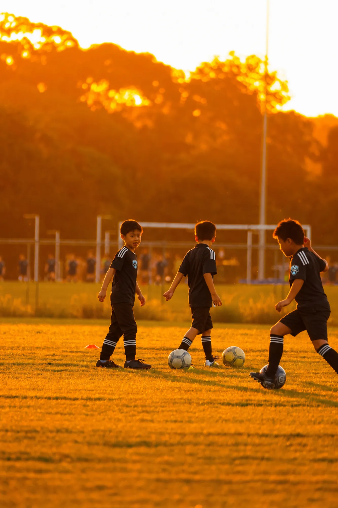 Kids playing soccer at sunset
