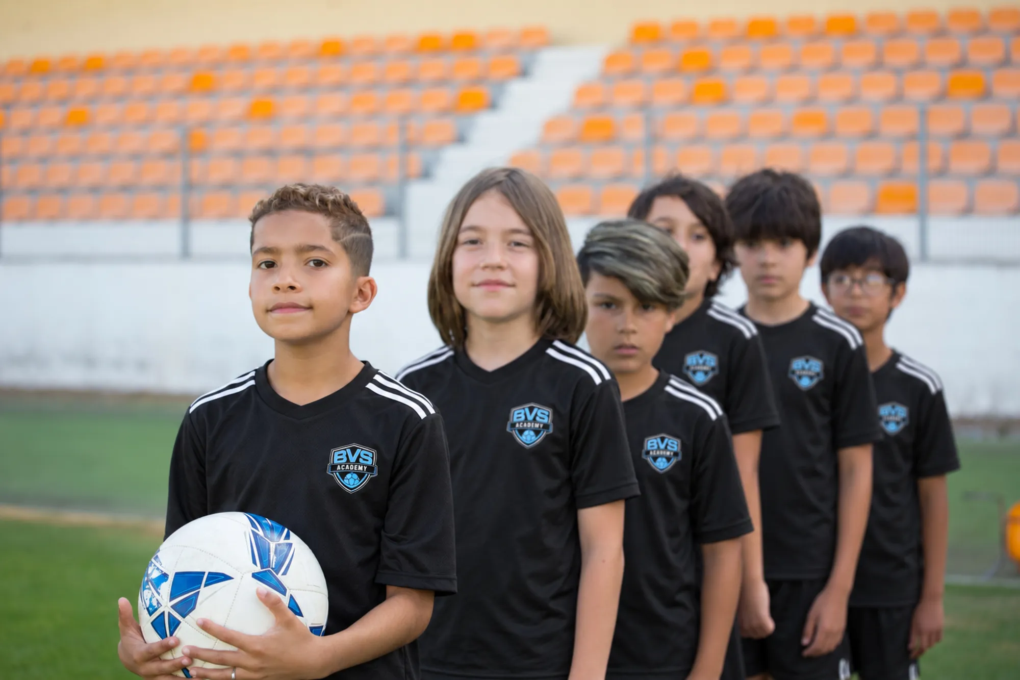 BVS Academy players lined up in their black kit, the first one holding the ball