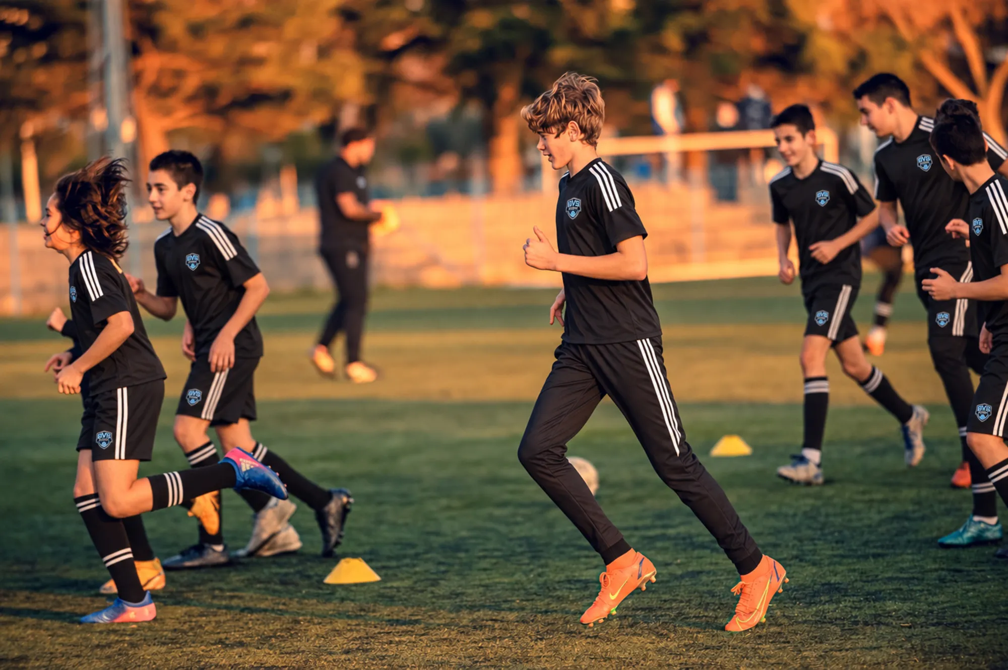 Players running a passing drill at dusk